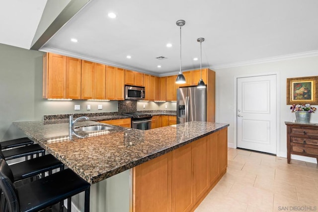 kitchen with a kitchen breakfast bar, appliances with stainless steel finishes, kitchen peninsula, sink, and decorative light fixtures