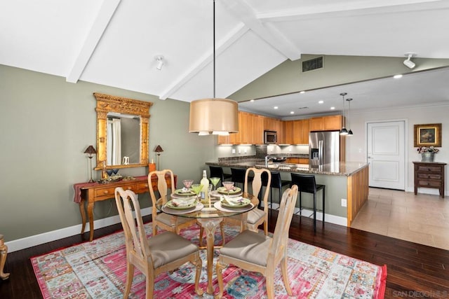 dining room featuring dark wood-type flooring, lofted ceiling with beams, and sink