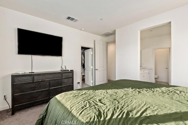 carpeted bedroom featuring ensuite bath, a walk in closet, and a closet