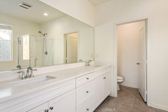 bathroom with vanity, a shower with shower door, tile patterned floors, and toilet