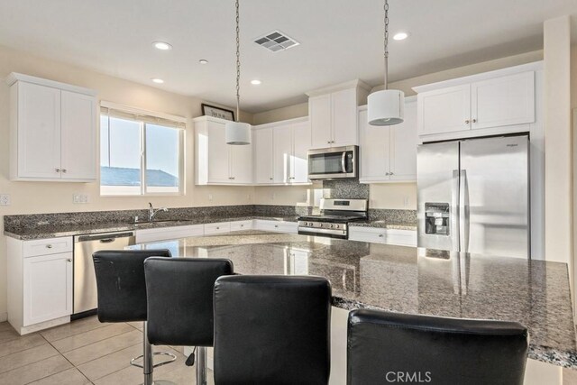 kitchen featuring pendant lighting, a center island, stainless steel appliances, a breakfast bar, and white cabinets