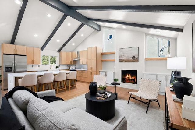 living room featuring sink, high vaulted ceiling, light hardwood / wood-style floors, and beamed ceiling