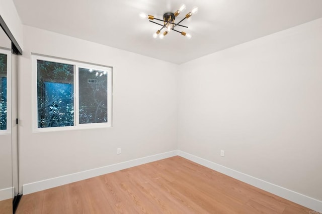 spare room featuring hardwood / wood-style flooring and an inviting chandelier