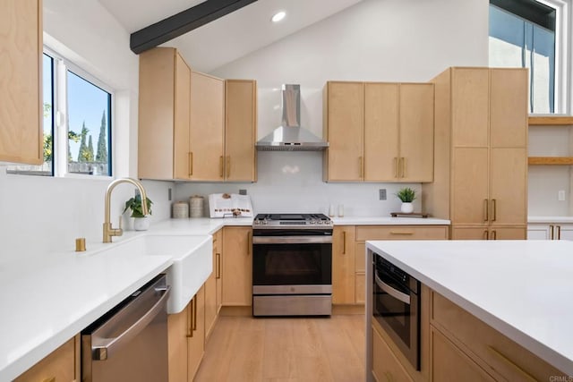 kitchen featuring sink, wall chimney exhaust hood, light brown cabinets, light hardwood / wood-style flooring, and appliances with stainless steel finishes