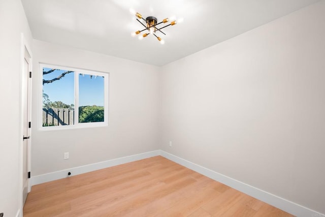 empty room with a notable chandelier and wood-type flooring