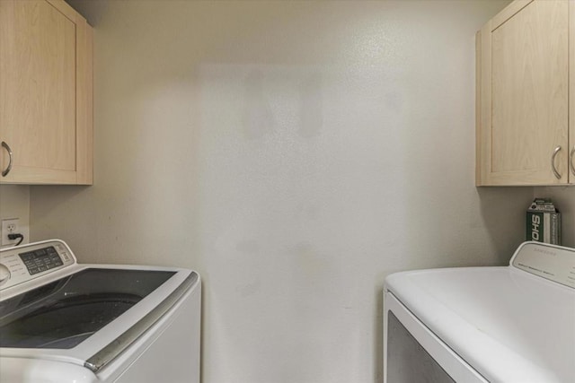 clothes washing area featuring cabinets and washer and clothes dryer