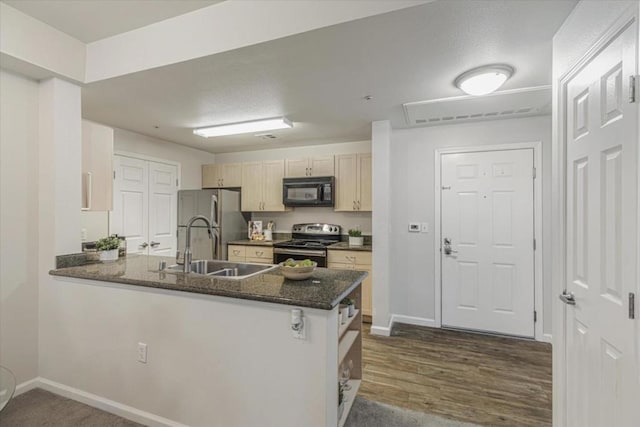 kitchen with sink, stainless steel appliances, dark stone counters, and kitchen peninsula