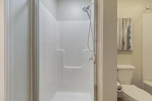 bathroom featuring walk in shower and toilet