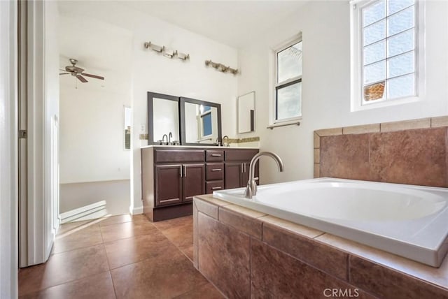 bathroom with ceiling fan, vanity, tile patterned flooring, and tiled tub