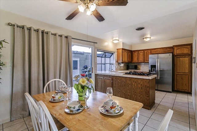 kitchen featuring a center island, gas stovetop, light tile patterned floors, tasteful backsplash, and stainless steel refrigerator with ice dispenser