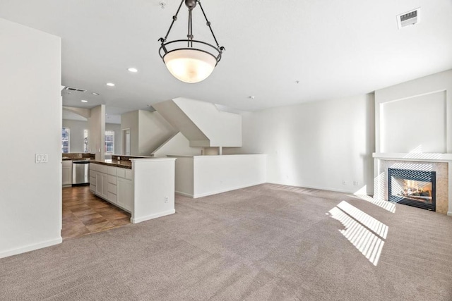 unfurnished living room featuring a tile fireplace and light carpet