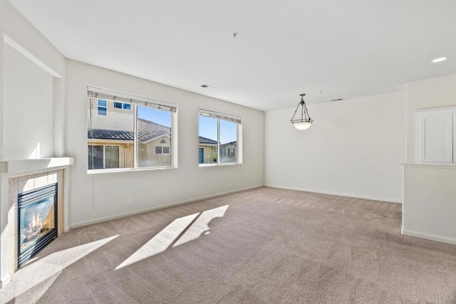 unfurnished living room with a tiled fireplace and light colored carpet