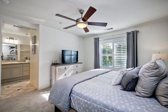 bedroom featuring sink, ceiling fan, light colored carpet, and ensuite bath