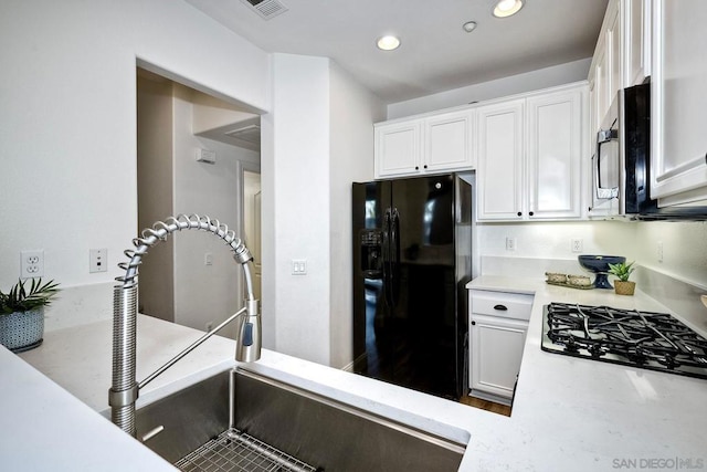 kitchen featuring sink, white cabinets, gas cooktop, and black fridge with ice dispenser