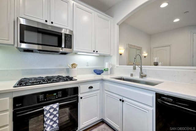 kitchen with black appliances, white cabinetry, and sink