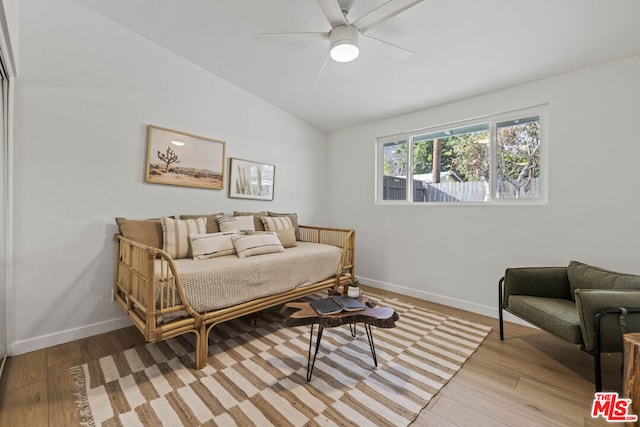 living room featuring ceiling fan, light wood-type flooring, and vaulted ceiling