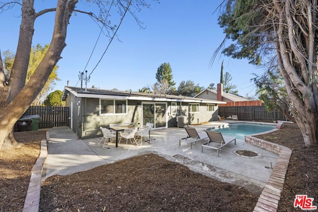 rear view of house featuring a fenced in pool and a patio