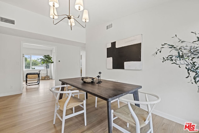 dining area with light hardwood / wood-style floors and a chandelier