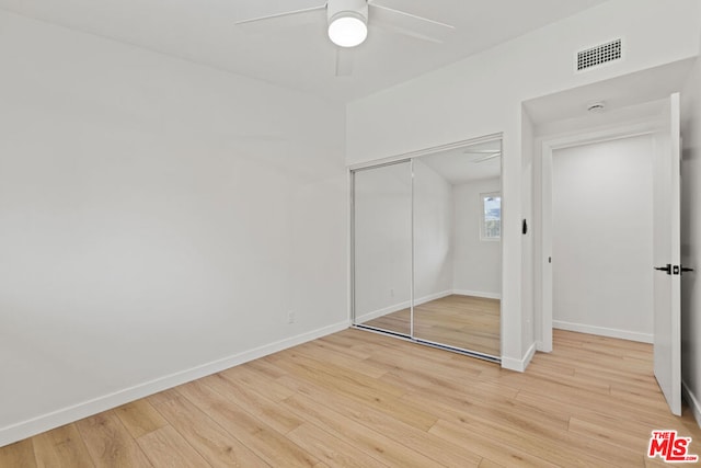 unfurnished bedroom featuring ceiling fan, a closet, and wood-type flooring