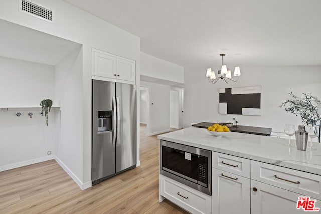 kitchen with light stone countertops, a chandelier, decorative light fixtures, white cabinetry, and appliances with stainless steel finishes