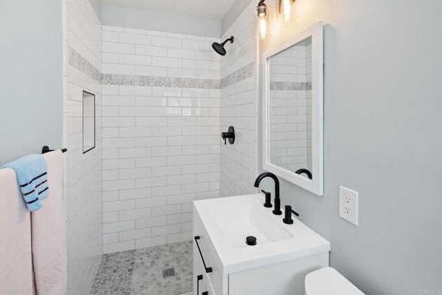 bathroom featuring vanity, toilet, and a tile shower