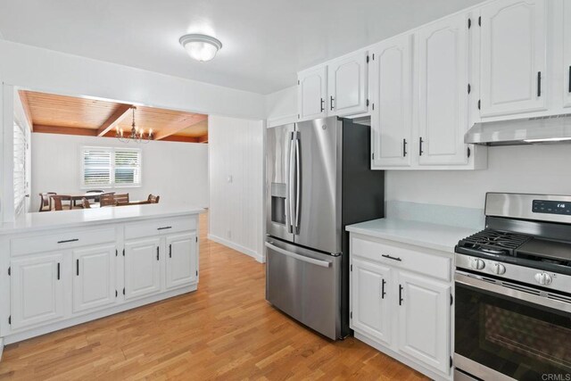 kitchen with an inviting chandelier, stainless steel appliances, light hardwood / wood-style floors, white cabinets, and wall chimney exhaust hood