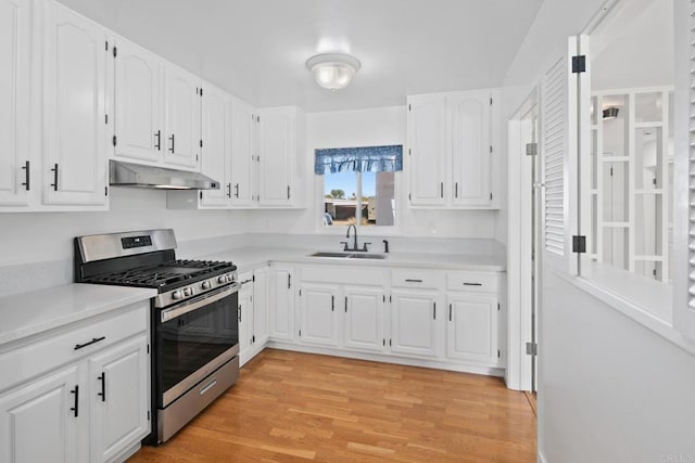 kitchen with white cabinetry, sink, gas range, and light hardwood / wood-style floors