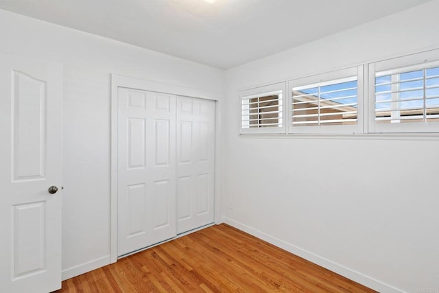 unfurnished bedroom featuring multiple windows, light hardwood / wood-style floors, and a closet