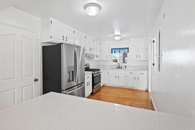 kitchen featuring appliances with stainless steel finishes, sink, white cabinets, and light hardwood / wood-style floors