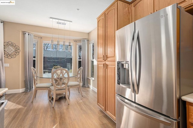 kitchen featuring light hardwood / wood-style floors, stainless steel fridge, and hanging light fixtures