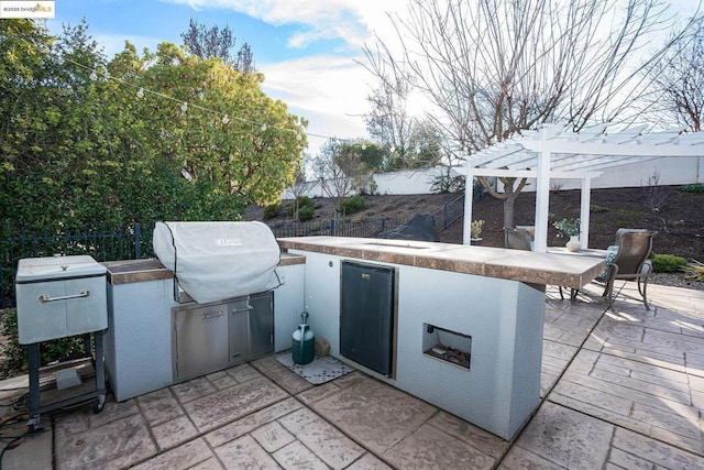 view of patio / terrace with exterior kitchen, area for grilling, and a pergola