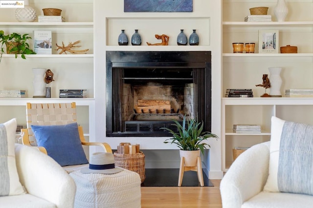 living area featuring hardwood / wood-style flooring, a fireplace, and built in shelves