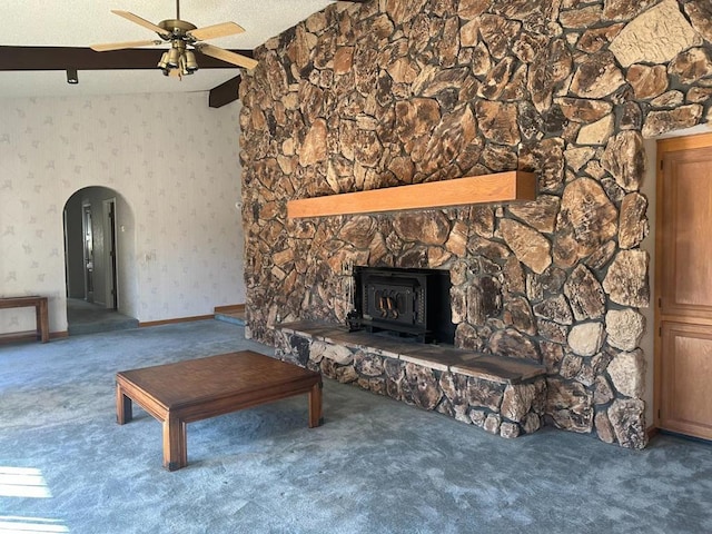 unfurnished living room featuring vaulted ceiling, carpet floors, ceiling fan, and a wood stove