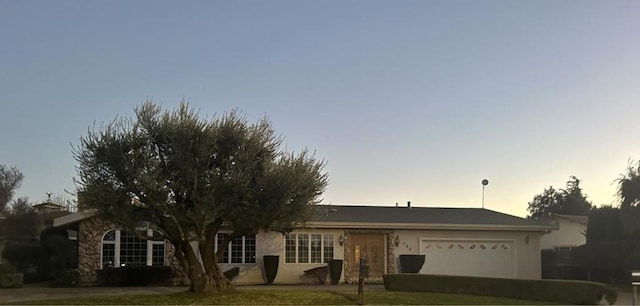 ranch-style home with a garage and a lawn