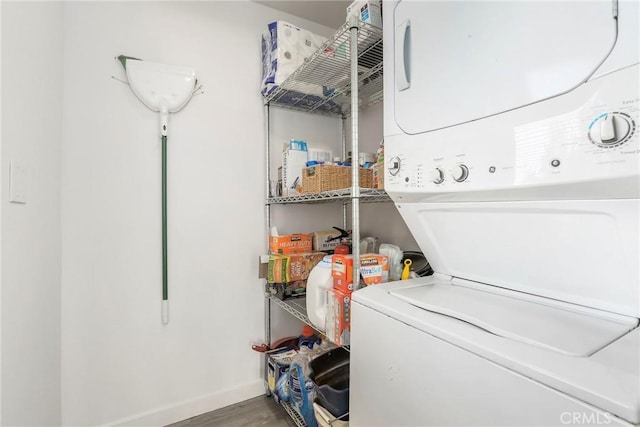 laundry room featuring stacked washer and dryer and hardwood / wood-style flooring