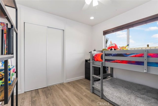 bedroom featuring ceiling fan, light hardwood / wood-style flooring, and a closet