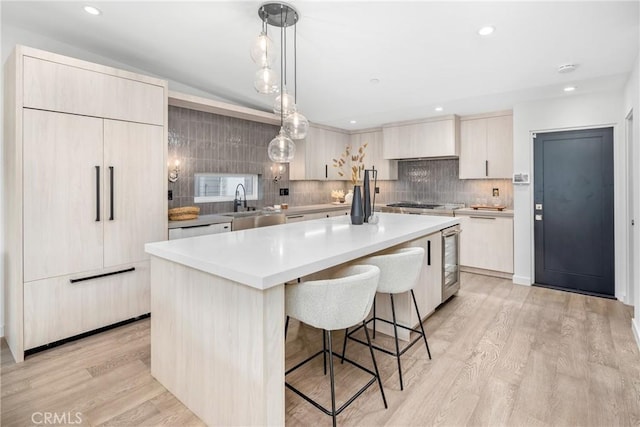 kitchen featuring pendant lighting, a kitchen island, sink, light hardwood / wood-style flooring, and backsplash