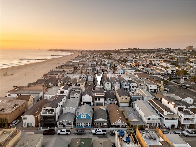 aerial view at dusk with a water view and a view of the beach