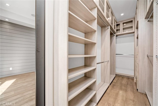 walk in closet with light hardwood / wood-style floors