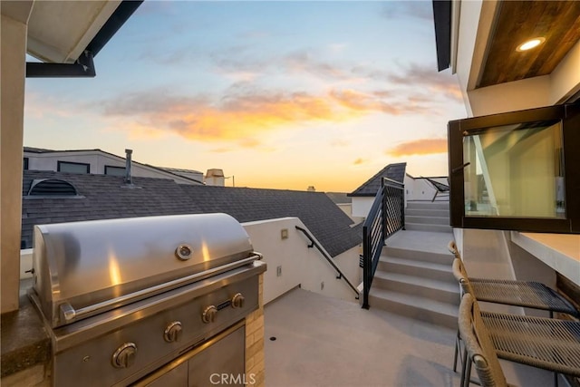 patio terrace at dusk featuring a grill and an outdoor kitchen