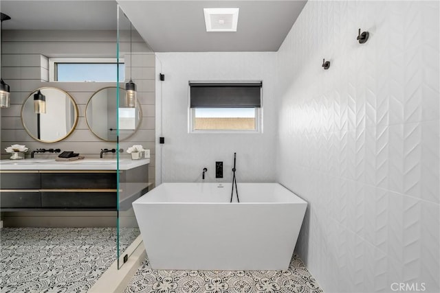 bathroom with tile patterned flooring, a tub to relax in, and vanity