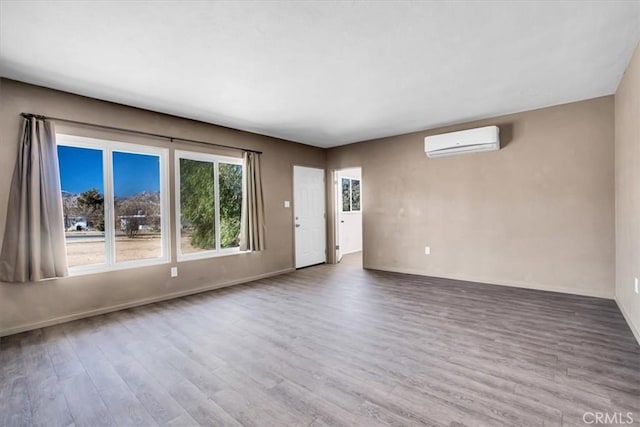 unfurnished room with a wall unit AC and hardwood / wood-style flooring