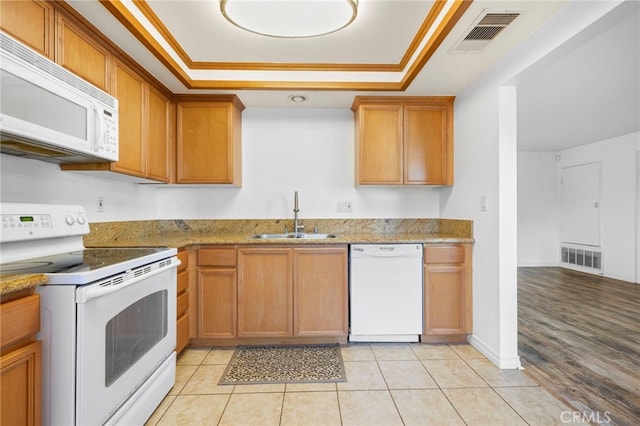 kitchen with sink, white appliances, crown molding, and a raised ceiling