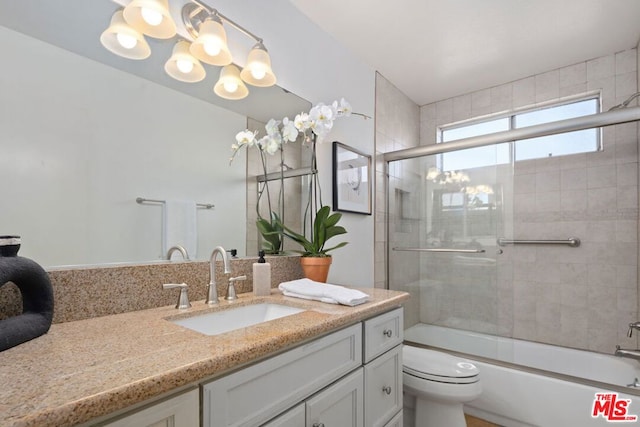 full bathroom featuring combined bath / shower with glass door, a chandelier, vanity, and toilet