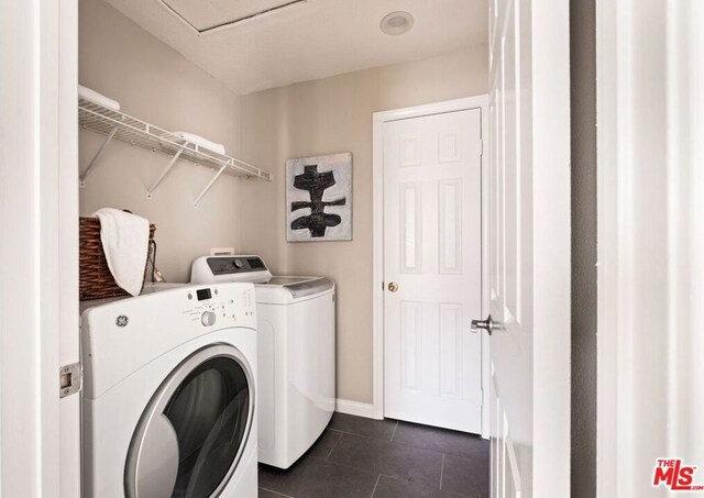 clothes washing area with washing machine and dryer and dark tile patterned flooring