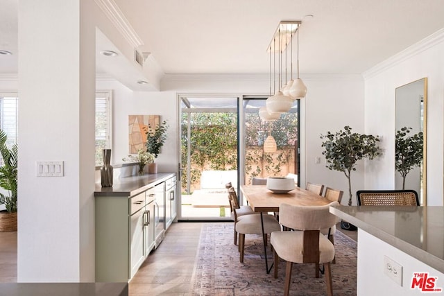 dining space with ornamental molding, a healthy amount of sunlight, and hardwood / wood-style flooring