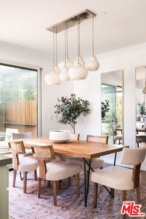 dining space with hardwood / wood-style flooring, ornamental molding, and a healthy amount of sunlight