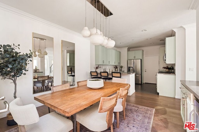 dining room with dark wood-type flooring, crown molding, and sink