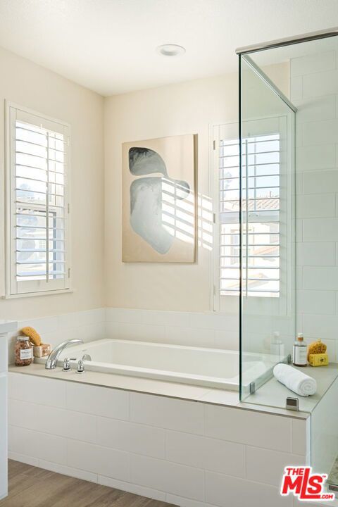 bathroom with hardwood / wood-style flooring and independent shower and bath