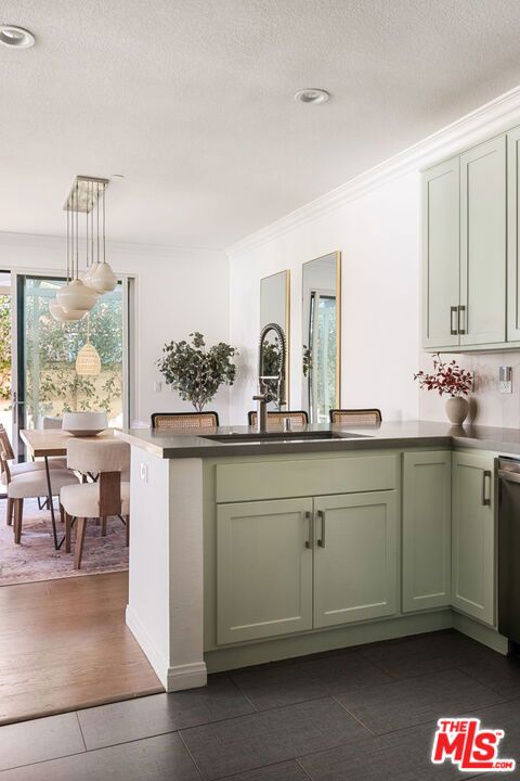 kitchen with sink, green cabinetry, hanging light fixtures, and dark tile patterned floors